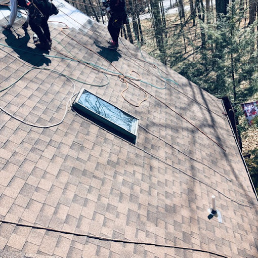 Roofing Contractors Finishing a Residential Shingle Roof Installation with a Skylight