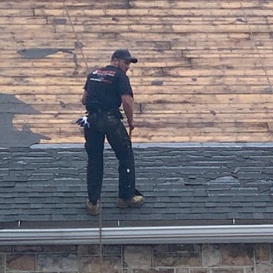 Roofing Contractor Scaling Stone Church After Removing Damaged Shingles During Roof Replacement